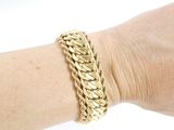 someone is wearing a gold bracelet with a braid design on it