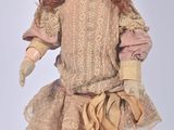 an old fashioned doll with red hair and a pink hat on a white surface