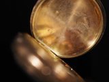 a close up of a gold pocket watch on a black background
