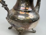 a silver tea pot with a handle on a stand