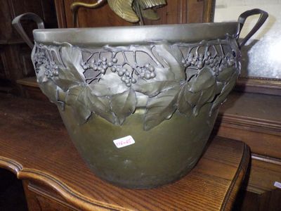 a large metal pot on a table with a bird on top of it