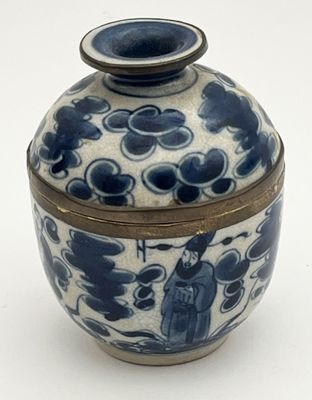un vase bleu et blanc muni d'un couvercle, posé sur une surface blanche