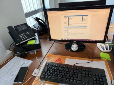 un bureau sur lequel se trouvent un ordinateur, un clavier, un téléphone et une imprimante