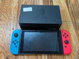 une Nintendo Switch Lite posée par terre à côté d'une boîte