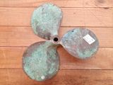 a metal propeller on a wooden floor with a tag on it