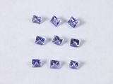 six square cut tanzane sapphires arranged in a row on a white surface
