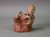 figurine of a woman reading a book on a gray surface