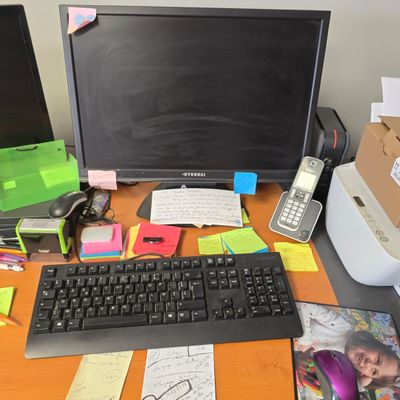 un bureau sur lequel se trouvent un ordinateur, un clavier, un téléphone et d'autres objets