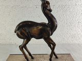 bronze statue of a gazelle on a marble base on a white background