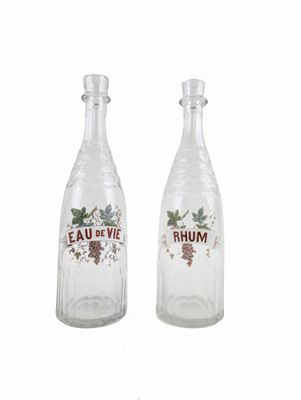 two clear glass bottles with red and green designs on them
