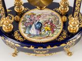 a blue and gold clock with a painting on it