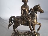 statue en bronze représentant un homme à cheval, posée sur un socle blanc