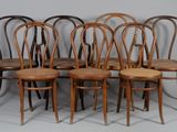 six chaises en bois sont alignées contre un mur gris