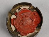 a close up of a red wax seal on a white surface
