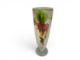 a glass vase with a flower on it on a white surface