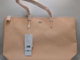 le sac est de couleur beige et porte une étiquette blanche