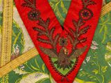 a red heart with a bird on it sitting on a green and yellow cloth