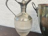 a silver vase next to a silver cup on a table