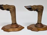 pair of carved wooden animal heads on pedestals on white background