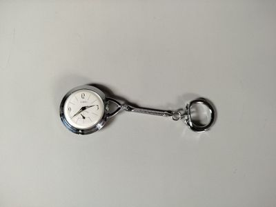 une montre de poche en argent à laquelle est attaché un porte-clés