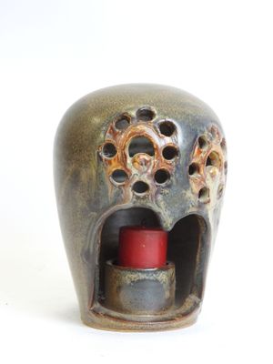 a small vase with a candle in it on a white surface
