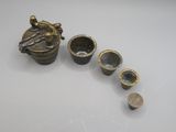un petit récipient en métal avec une cuillère et des tasses posés sur une table