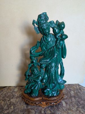 une statue verte représentant une femme tenant un bébé dans ses bras