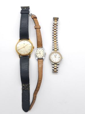 Deux montres et un bracelet de montre sont posés sur une surface blanche