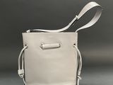 beige leather bucket bag with white cord handle and strap