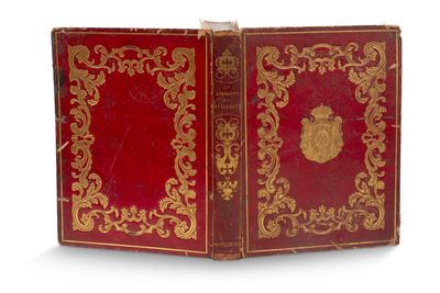 un vieux livre rouge aux bords dorés et orné d'un emblème doré sur la couverture