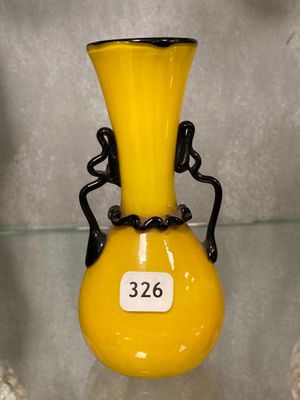 a yellow vase with a black handle on a glass shelf