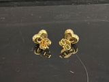 a pair of gold plated earrings on a black surface
