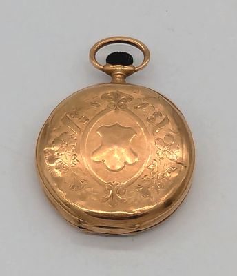 une montre de poche en or sur une surface blanche