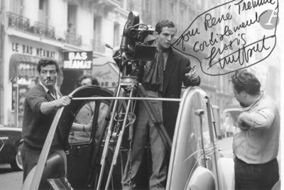 black and white photograph of a man standing next to a car with a camera on it