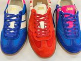 three pairs of colorful sneakers sitting on top of a white table