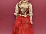 an old doll is standing on a red surface with a red background