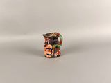 an orange and black vase sitting on top of a white table