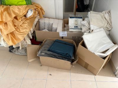 un tas de vêtements et d'autres objets rangés dans des cartons posés par terre
