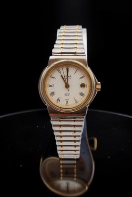 an image of a gold and silver watch on a black surface
