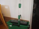 a mop that is sitting on the floor next to a green bucket