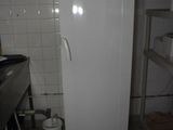a white refrigerator in a small kitchen with a bucket on the floor
