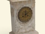 une horloge blanche avec un cadran doré, posée sur un socle