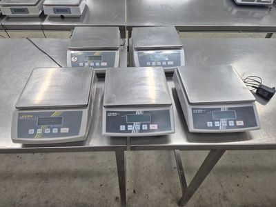 cinq balances électroniques posées sur une table dans une pièce