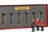 trois figurines de soldats debout devant une boîte rouge