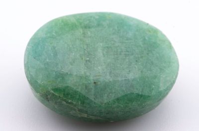 un gros plan d'une pierre verte sur une surface blanche