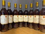 six bottles of wine are lined up on a wooden barrel
