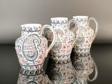 trois vases sont alignés sur une surface noire où l'on voit un reflet