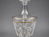 a clear glass decanter with gold trimming and a wooden stopper