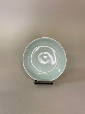un petit bol posé sur un socle, sur une surface blanche