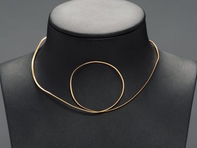 a black mannequin with a gold necklace on it